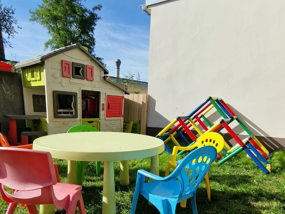 Rasenfläche mit runder Kindersitzgruppe, Spielhaus und Klettergerüst